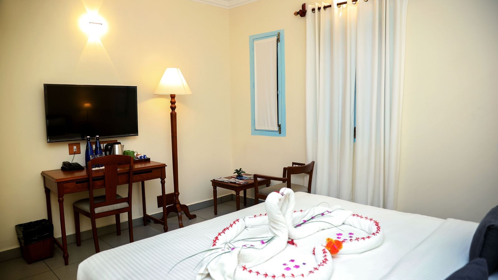 A bedroom which has a bed decorated already and a flatscreen TV | Mango Hill La Serene, Pondicherry