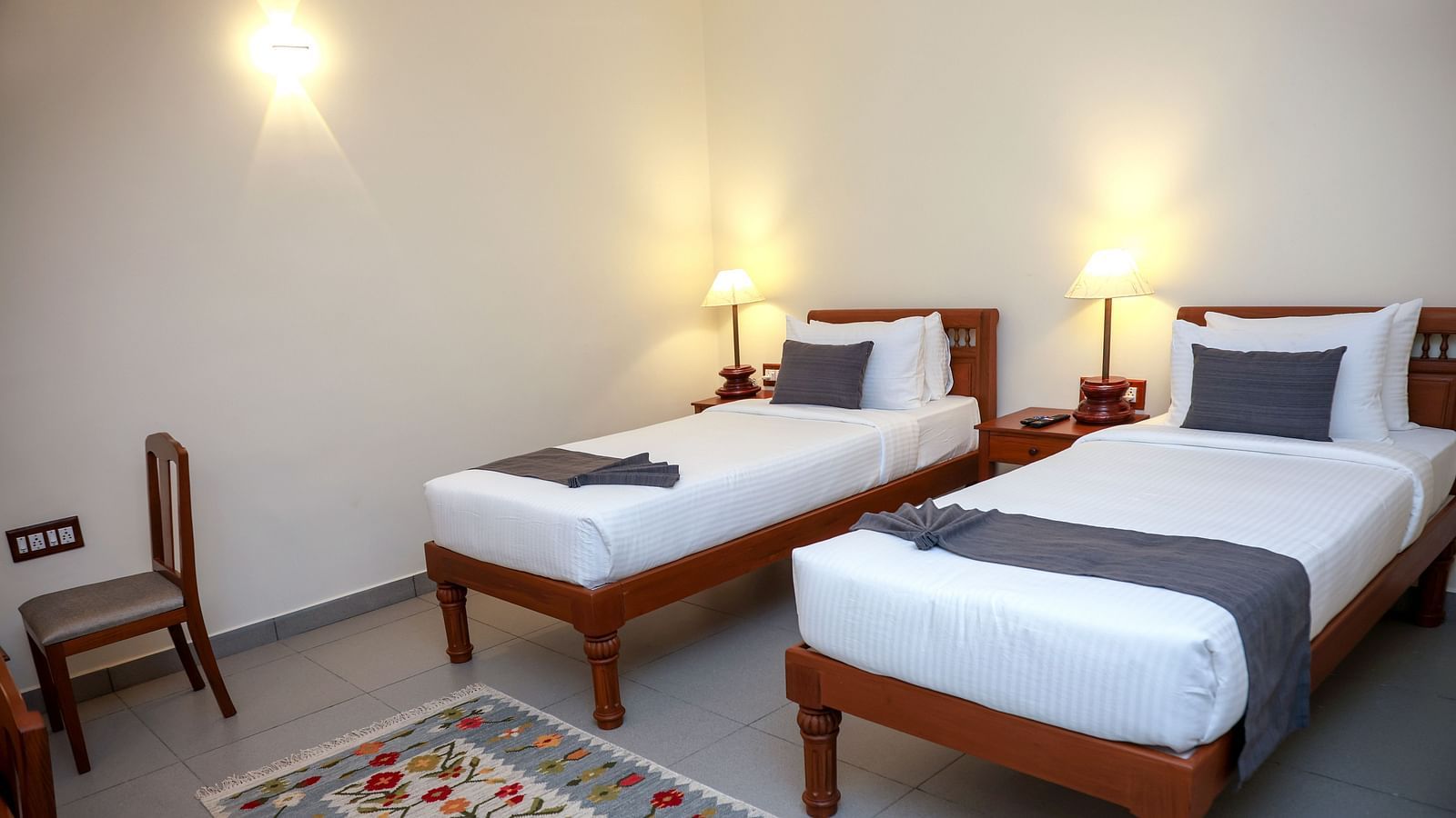 Twin beds and a chair in a room  |Mango Hill La Serene, Pondicherry
