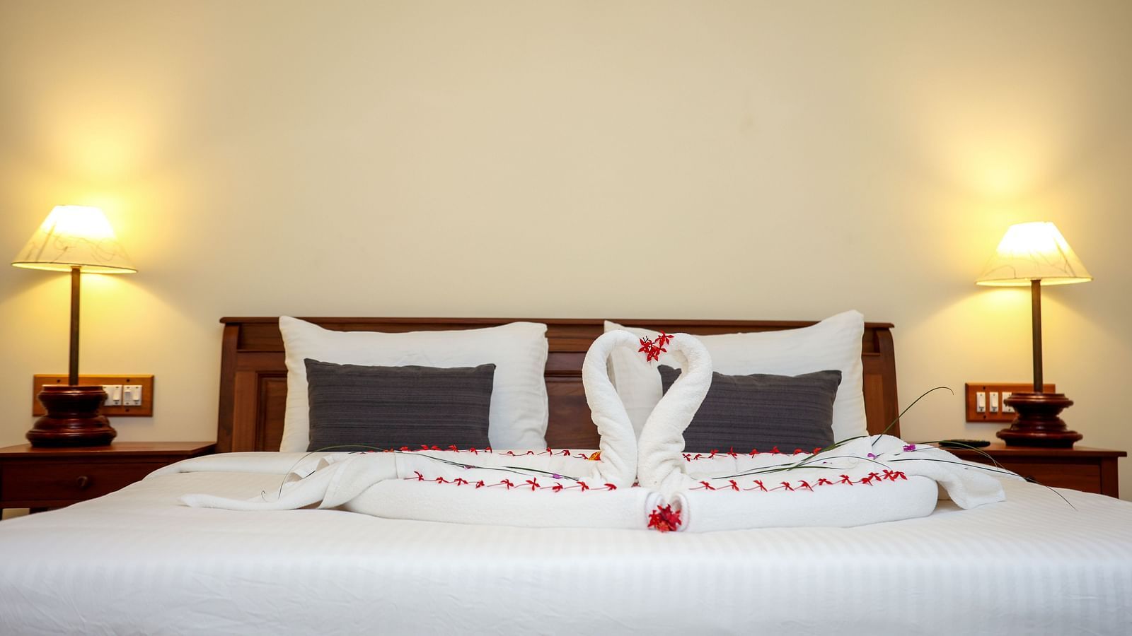 A large bed decorated with towel swans and flower petals | Mango Hill La Serene, Pondicherry