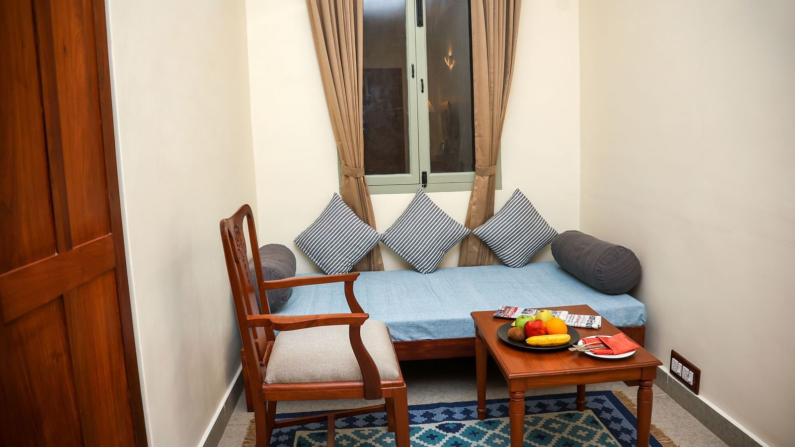 A sitting area with sofa, cushions, wooden chair and a centre table | Mango Hill La Serene, Pondicherry