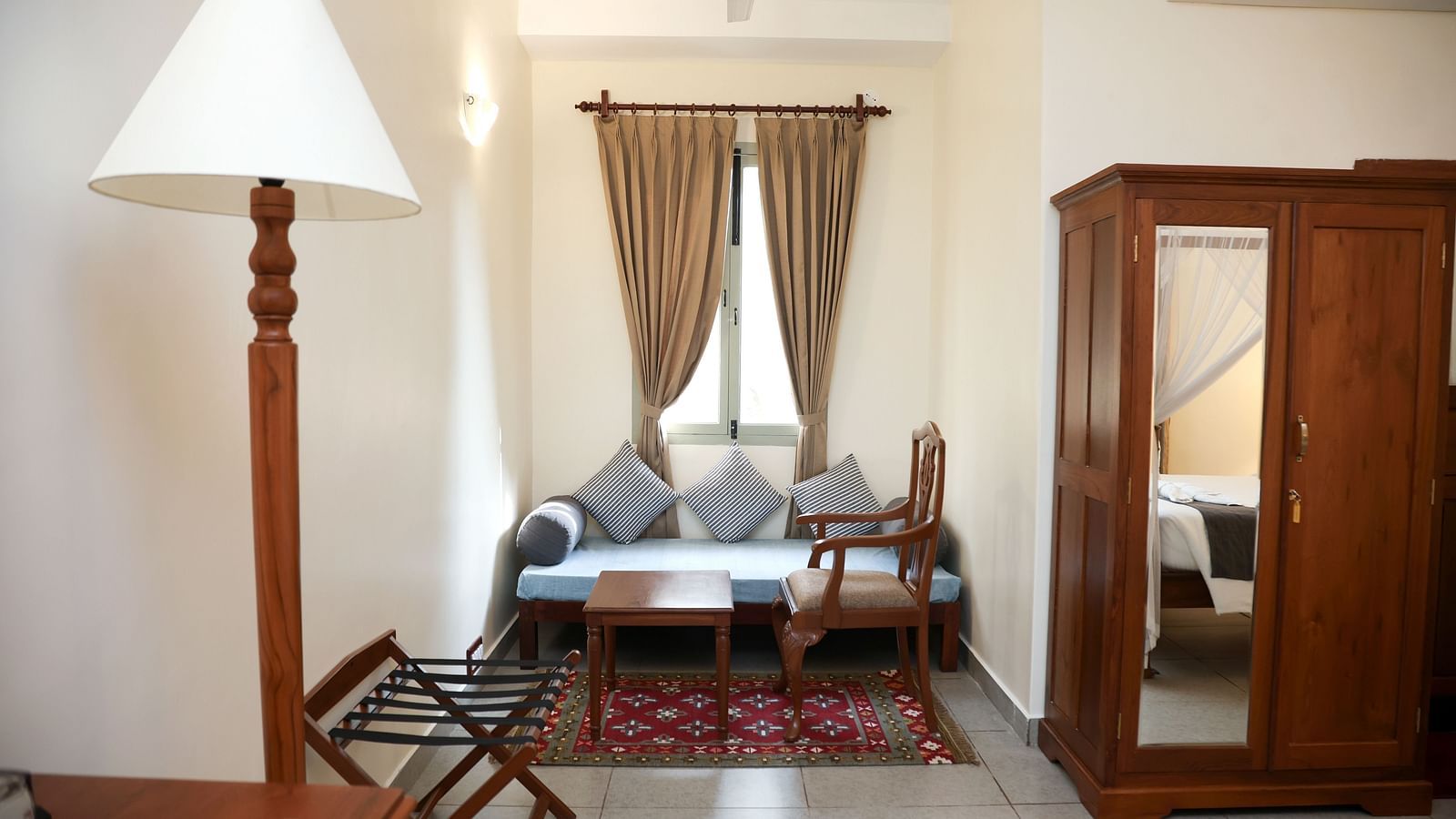 A room that has a sitting area, a cupboard, and a tall lamp | Mango Hill La Serene, Pondicherry