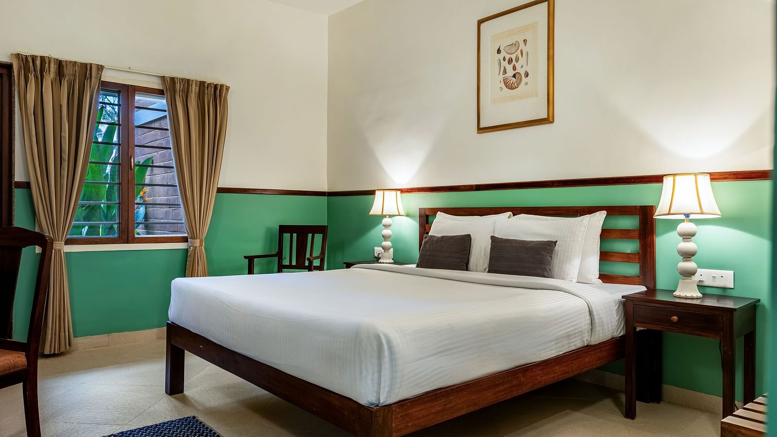 Comfortable bedroom with a wooden bed frame, white linens, bedside lamps, a framed picture, and a window with draped curtains | Mango Hill Shallow Beach Resort ECR