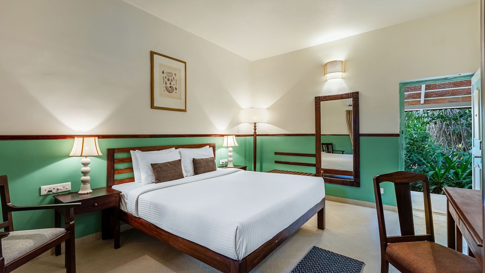 Comfortable bedroom with a wooden bed frame, white linens, bedside lamps, a framed picture, and a window with draped curtains | Mango Hill Shallow Beach Resort ECR