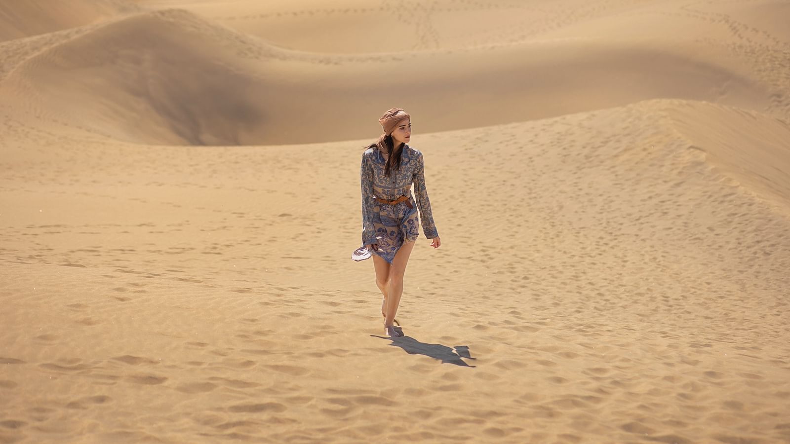 Long shot of a woman walking alone  on a desert.
