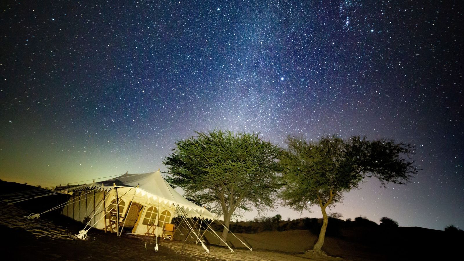 A breathtaking sunset view over the desert, with the campsite situated along the trail, highlighting the vastness of the landscape - MANVAR Resort & Desert Camp