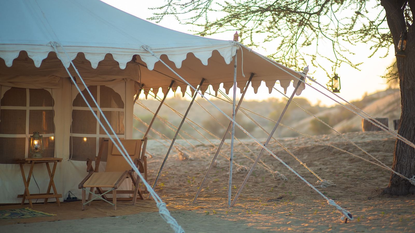 A spacious canvas tent with stylish frills, securely placed in the desert, stands ready for a luxurious escape in the golden light of dusk or dawn. - at Manvar Resort 