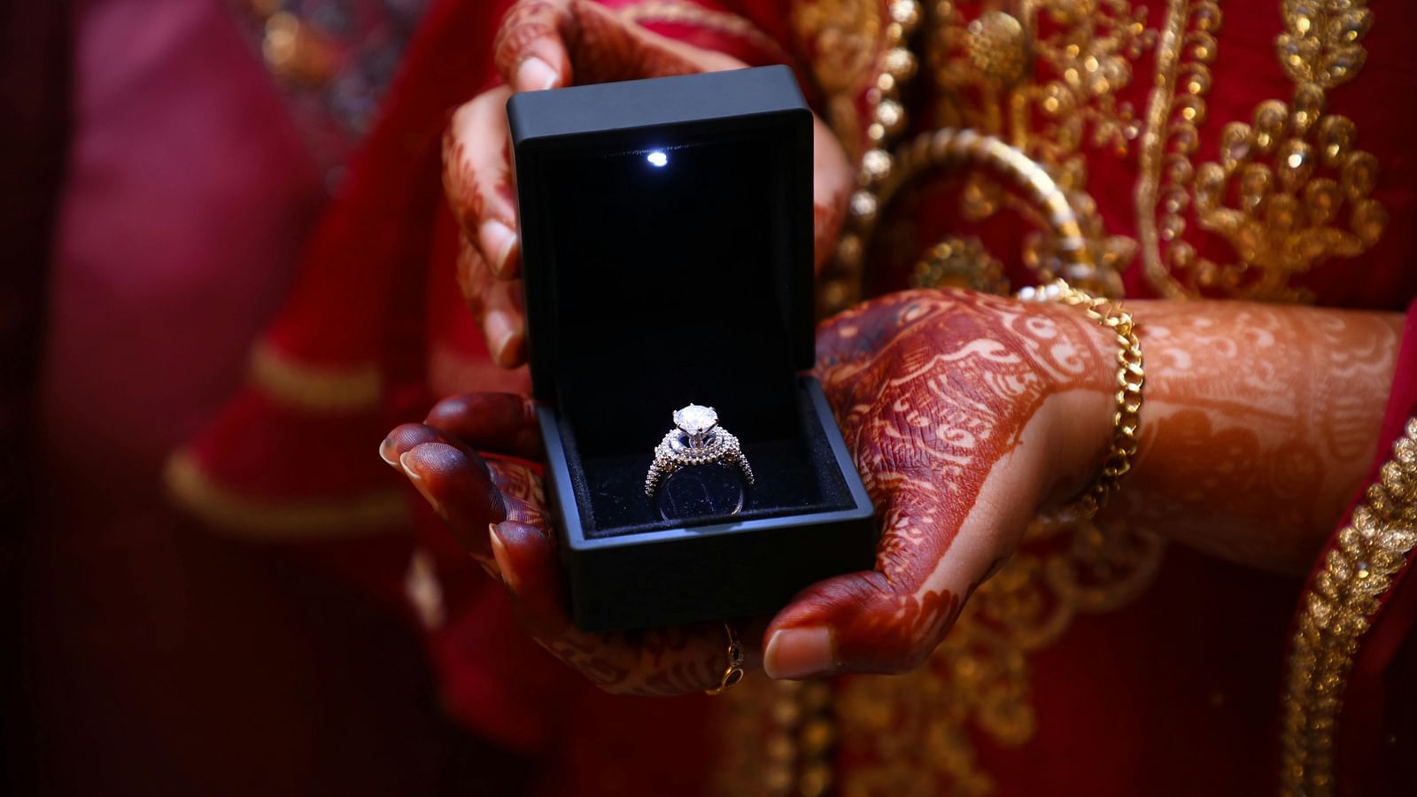 A close-up shot of a bride holding an engagment ring in a box
