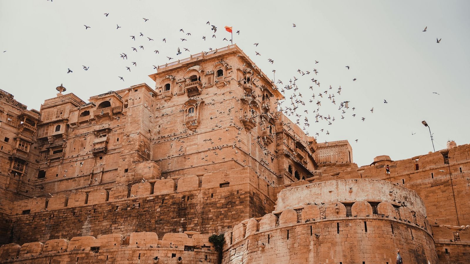 A view from below of a fort in jaisalmer with birds flying away
