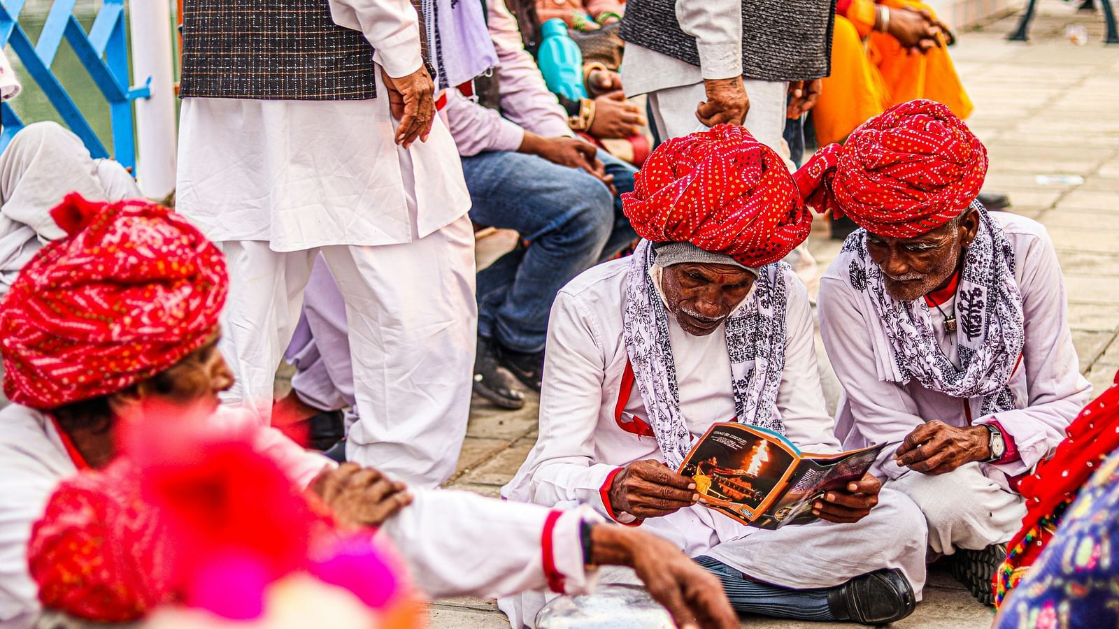 a group of rajasthani people sitting on the ground and reading a book