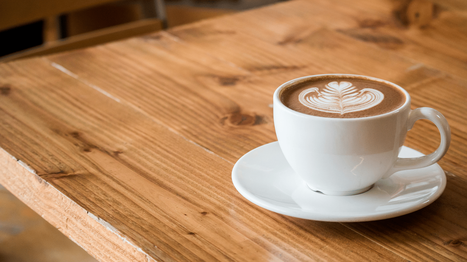 A cup of coffee on a wooden table.