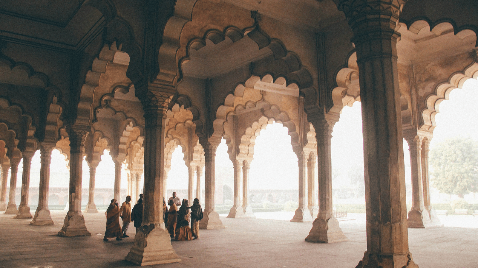 A group of people standing near pillars of a building twmwlx