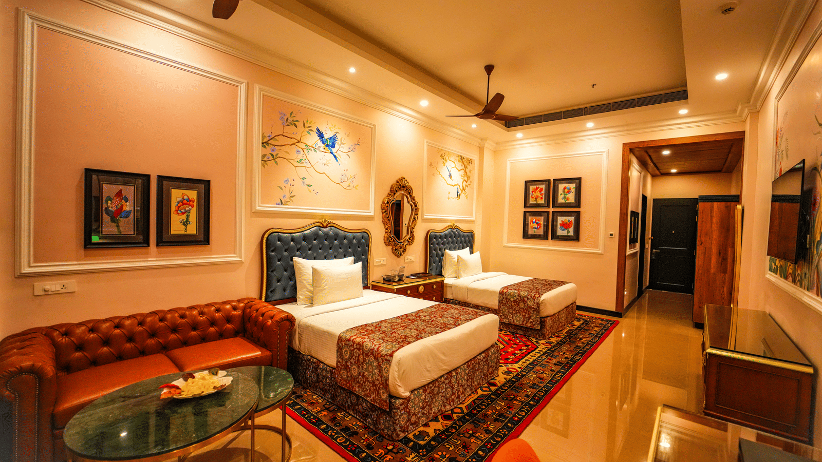 Executive Room at MAYFAIR Oasis Resort featuring twin beds, plush red sofa, and elegant interior decor.