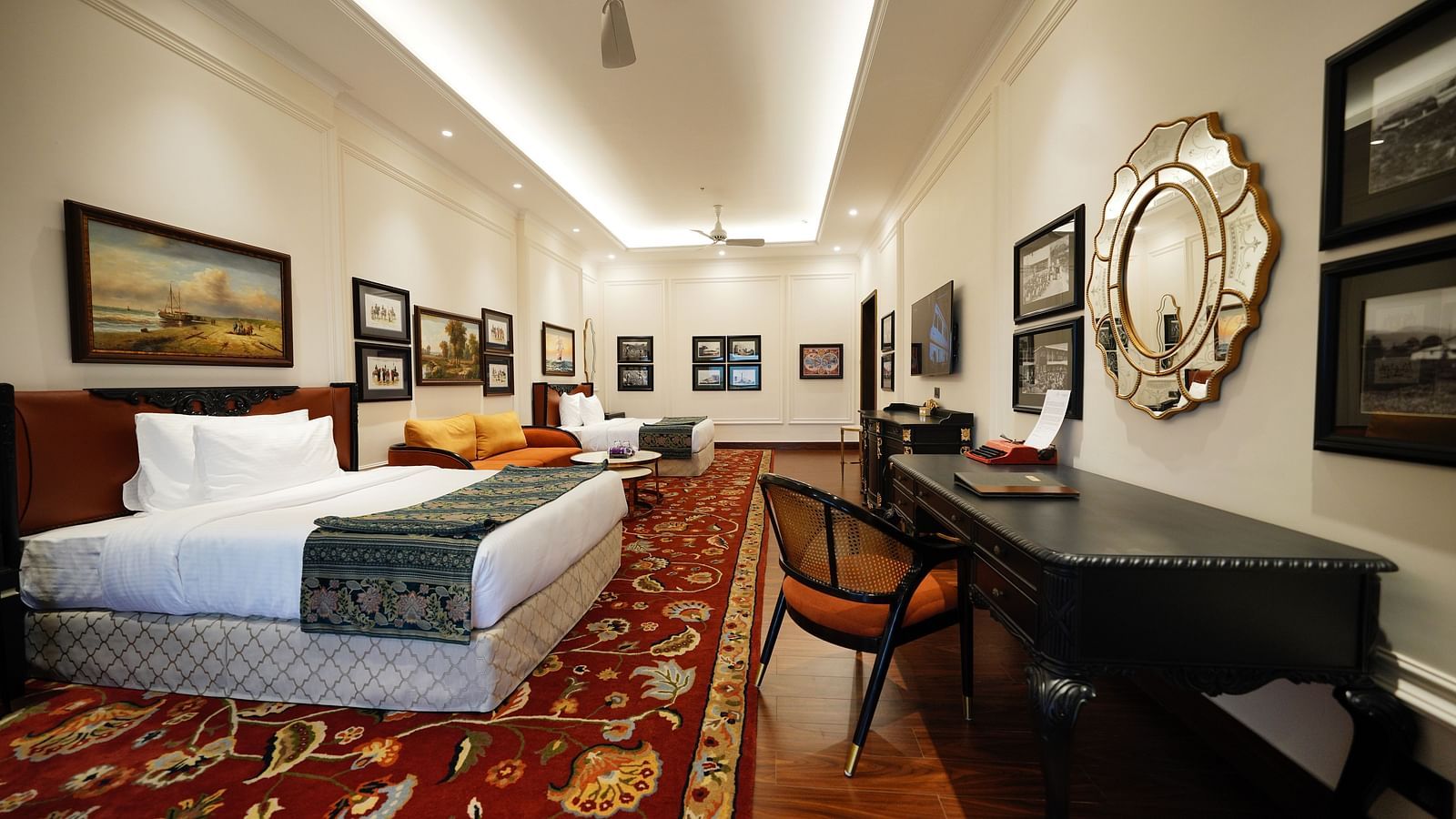 Bright guest room with red armchair and framed art at MAYFAIR Tea Resort, Siliguri