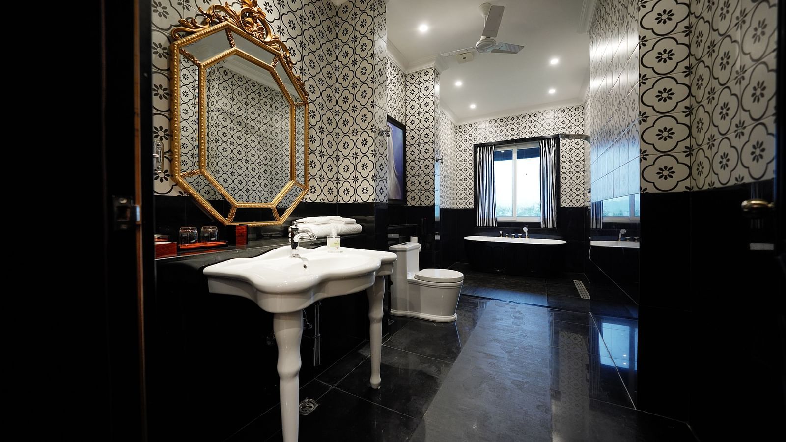 Elegant black-and-white bathroom with vintage gold-framed mirror at MAYFAIR Tea Resort, Siliguri