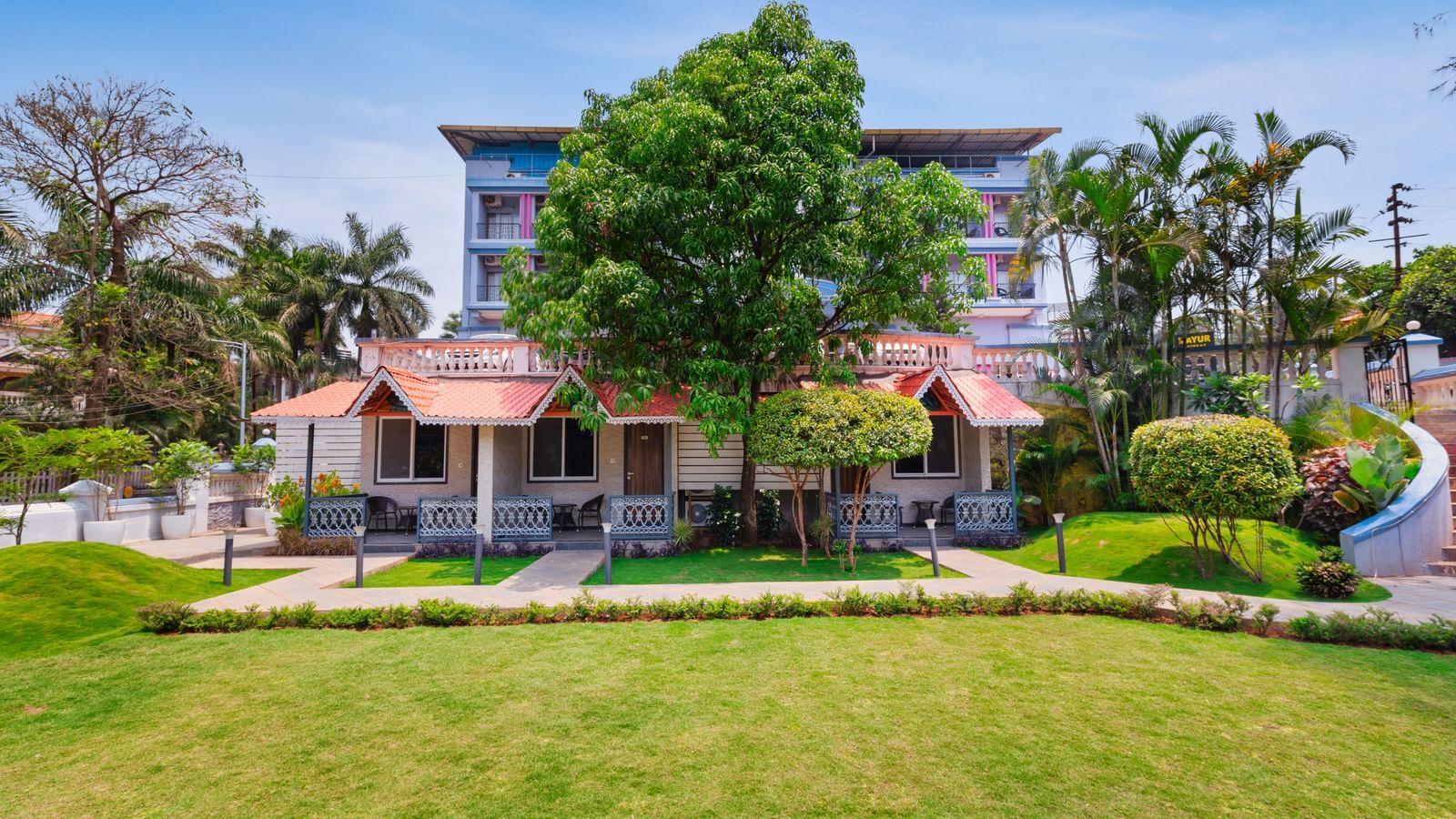 Facade view of cottage-style accommodations at Mayur Retreat surrounded by greenery. 