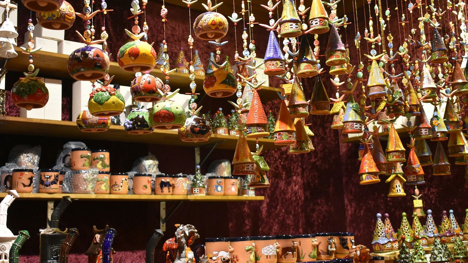 Display of colourful handcrafted pottery and hanging ceramic decorations in a vibrant store setting.