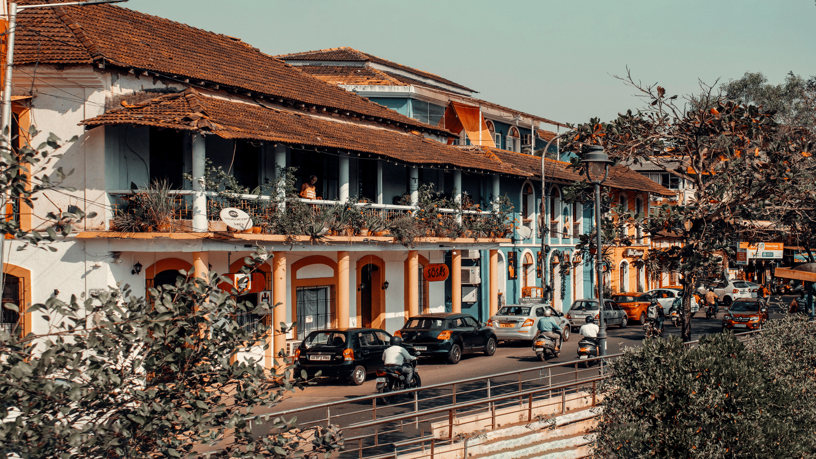 A scenic narrow street view of colourful yellow and blue colonial-style buildings.