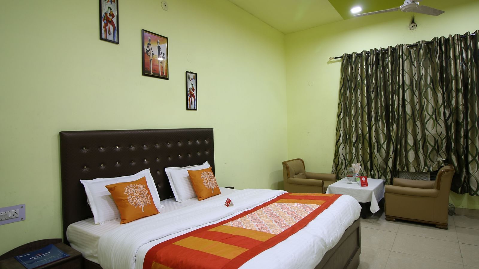 An image of our Family Suite in Roorkee with a large bed, a ceiling fan, two couches and a teapoy - Motel Divine International, Roorkee