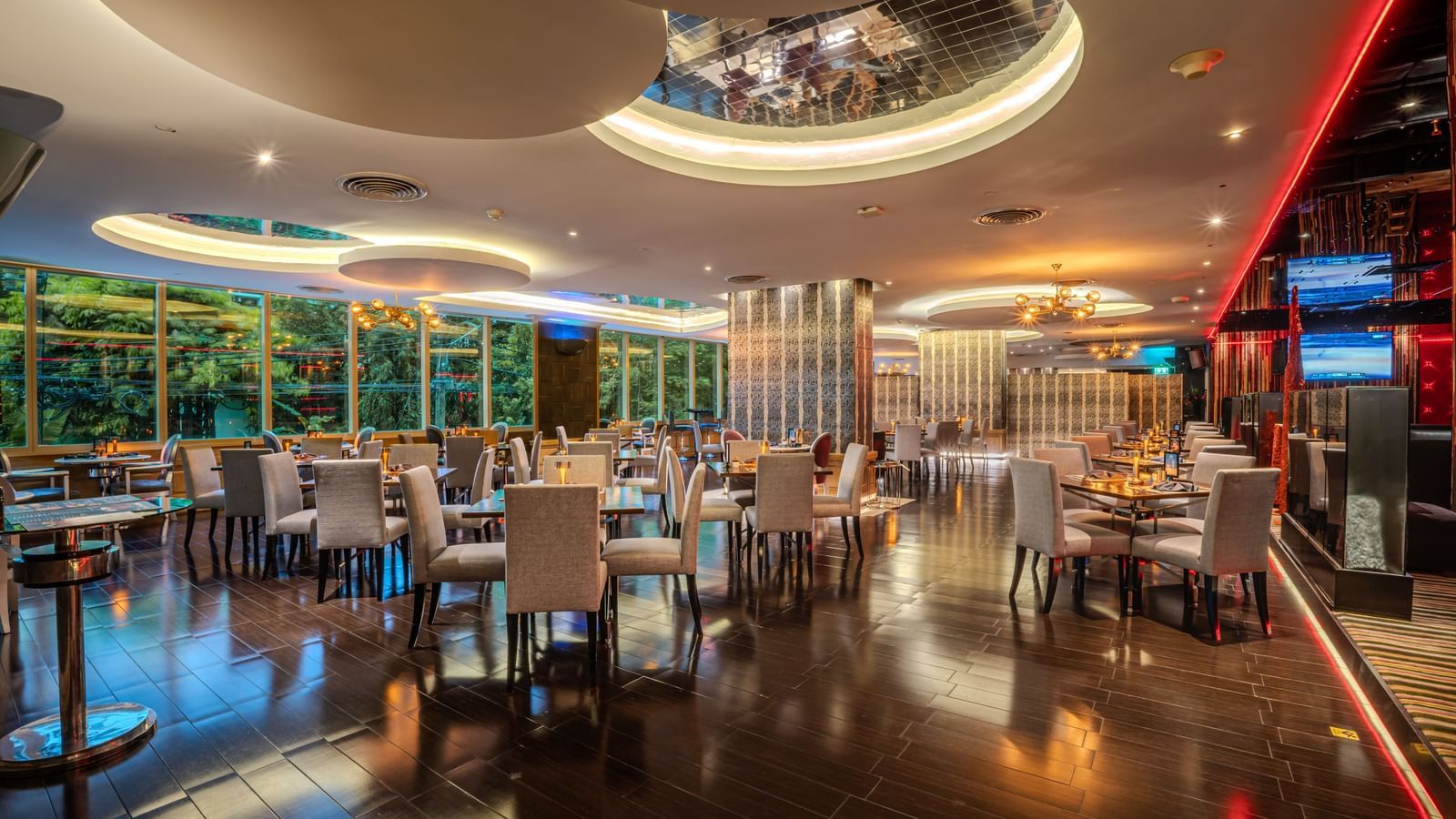 An overview of the seating arrangements inside a restaurant with chandeliers and floor to ceiling glass in view - Night Hotel Bangkok.