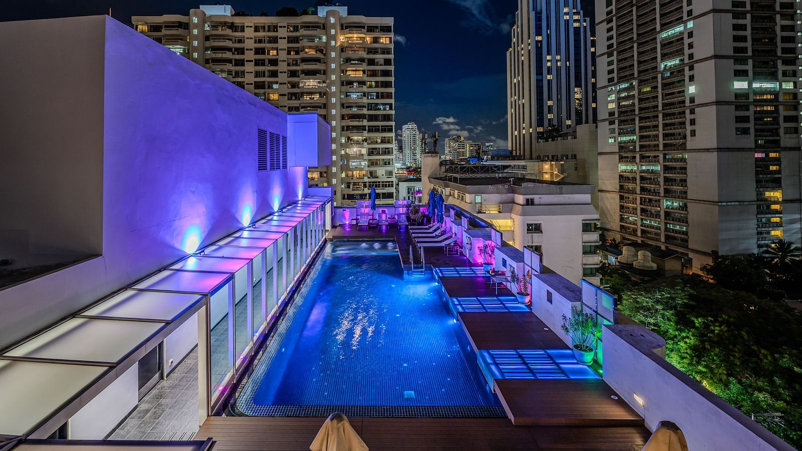 An overview of the rooftop swimming pool with the lights on  - Night Hotel Bangkok.