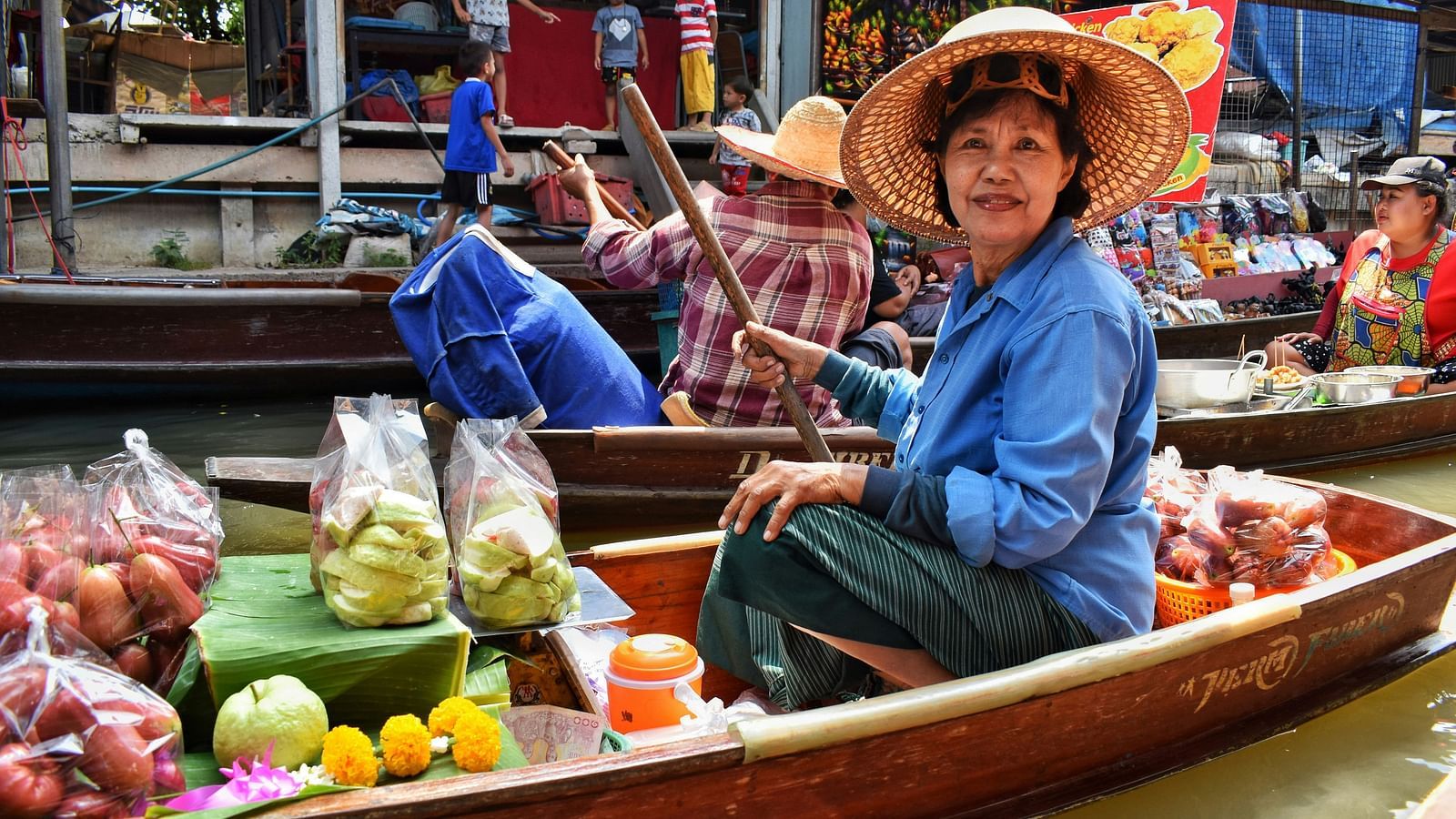 a person selling cut fruits in a floating market posing for a picture.