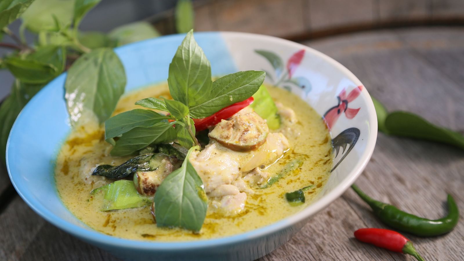 A close up of Green Curry (Gaeng Keow Wan) with leaves kept on top as garnishing.