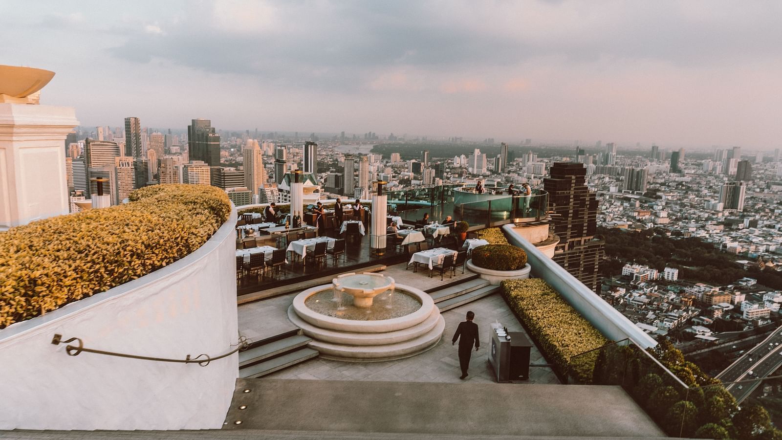 a rooftop bar in Bangkok with a city view and seating on the terrace.