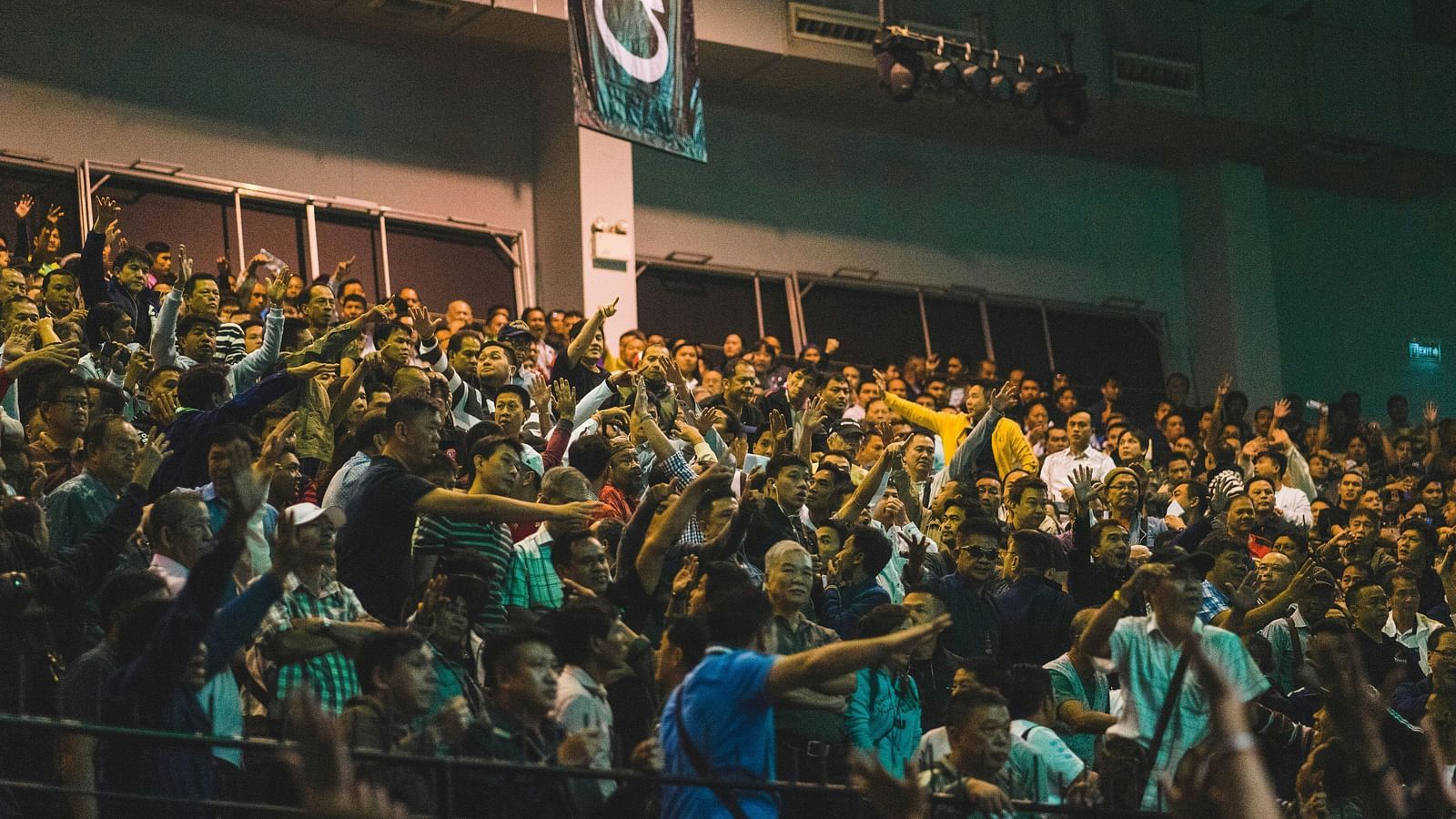 a crowd cheering and shouting while watching a muay thai fight