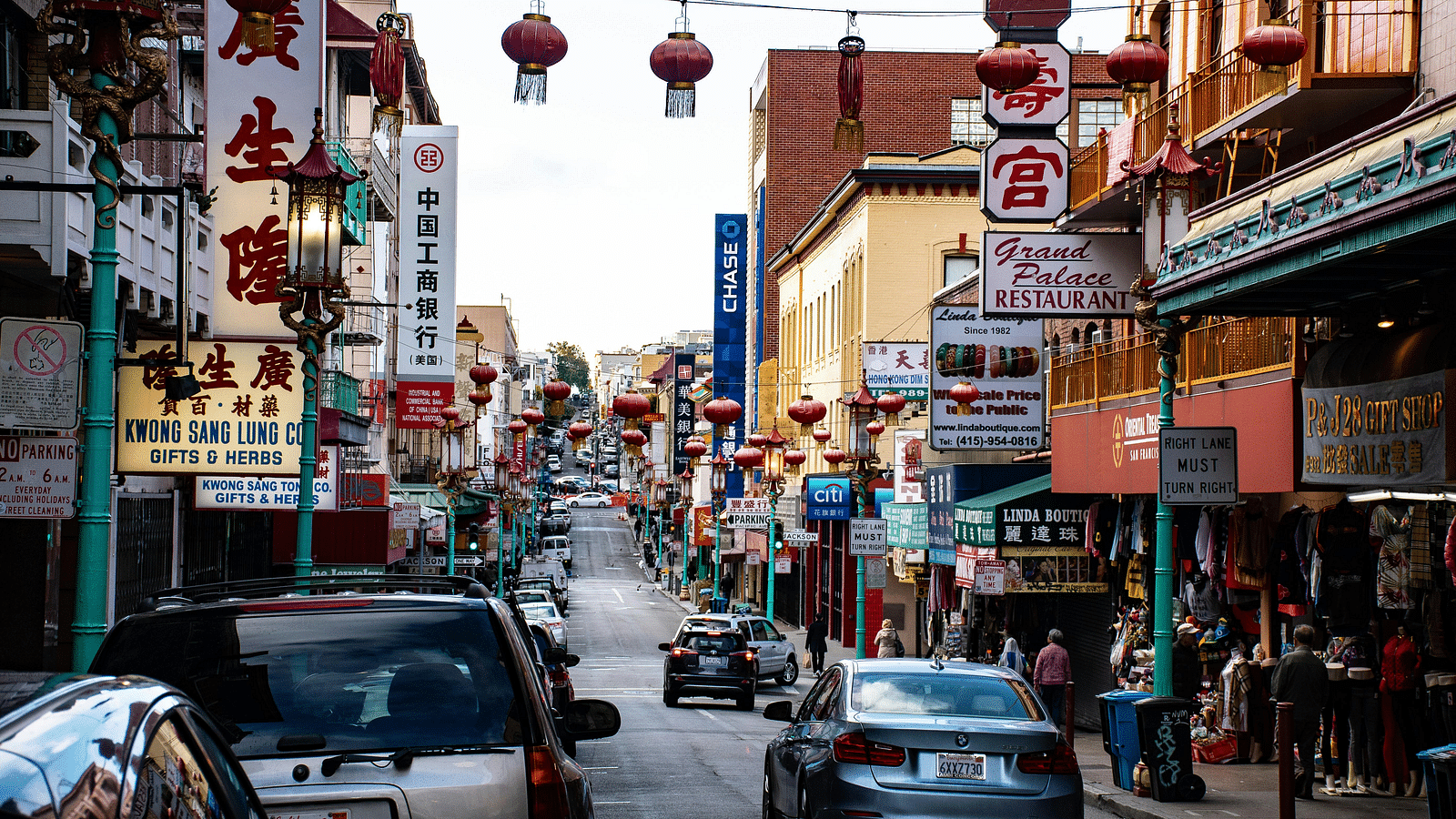 a street with cars and people and billboards with captions in chinese written on them