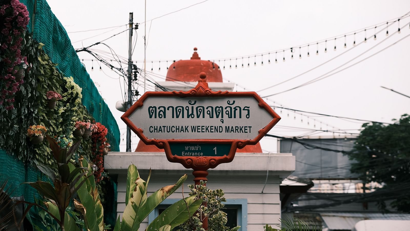 a signage of Chatuchak Weekend Market at the entrance of the event space with white clouds in the background