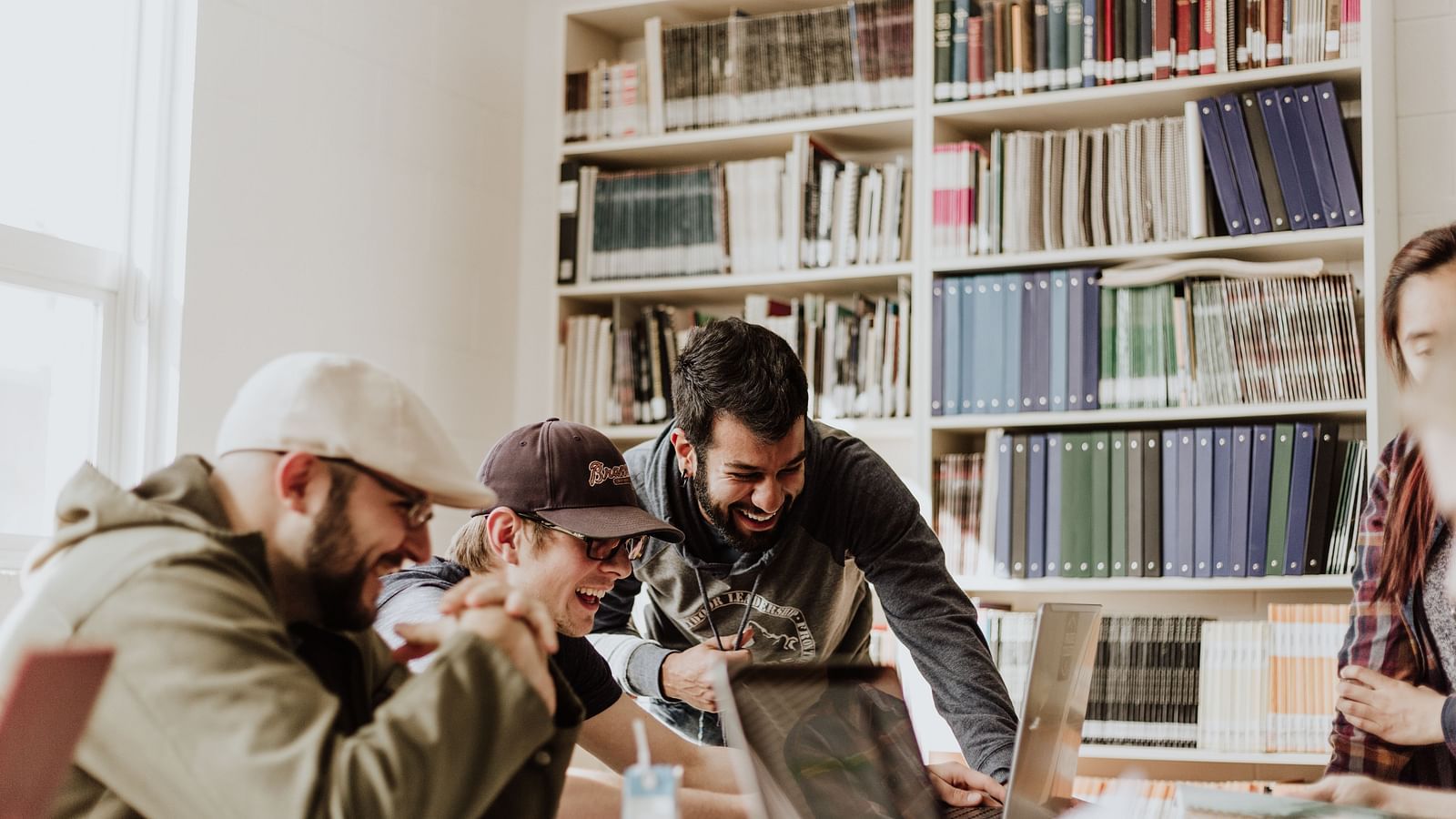 A group of people from different countries in a library working on a computer