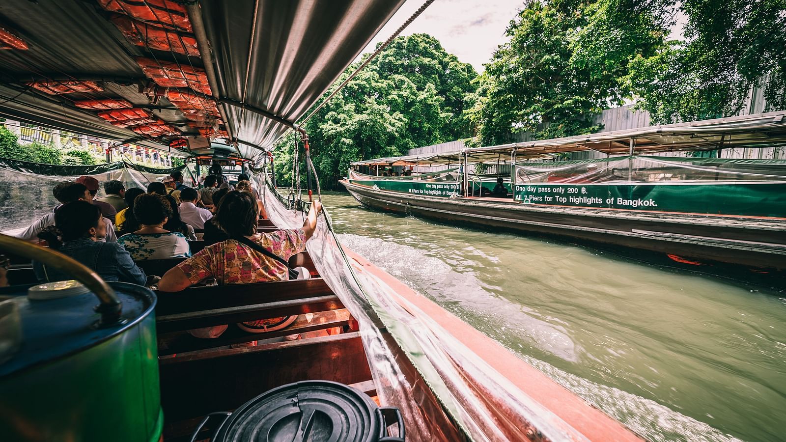 a boat travelling on a waterbody in Bangkok with buildings on the side