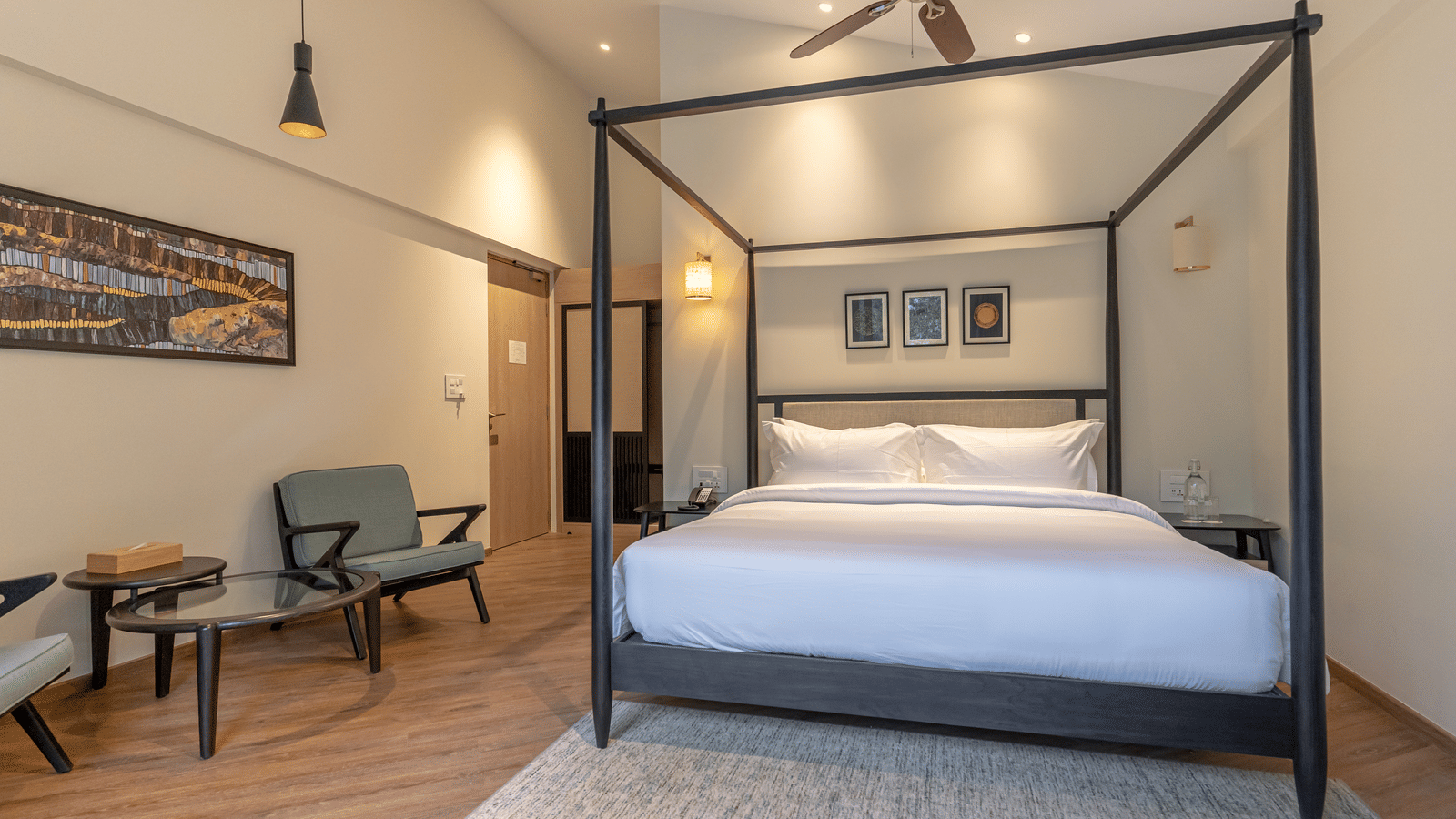 Spacious bedroom with a four-poster bed and seating area at Nivasana Manali.