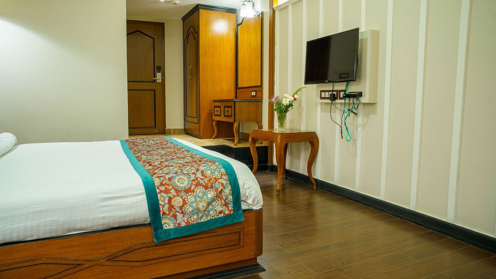 A room at Orsino Spa Resortwith a bed, a television mounted on the wall, and light-coloured striped wallpaper.