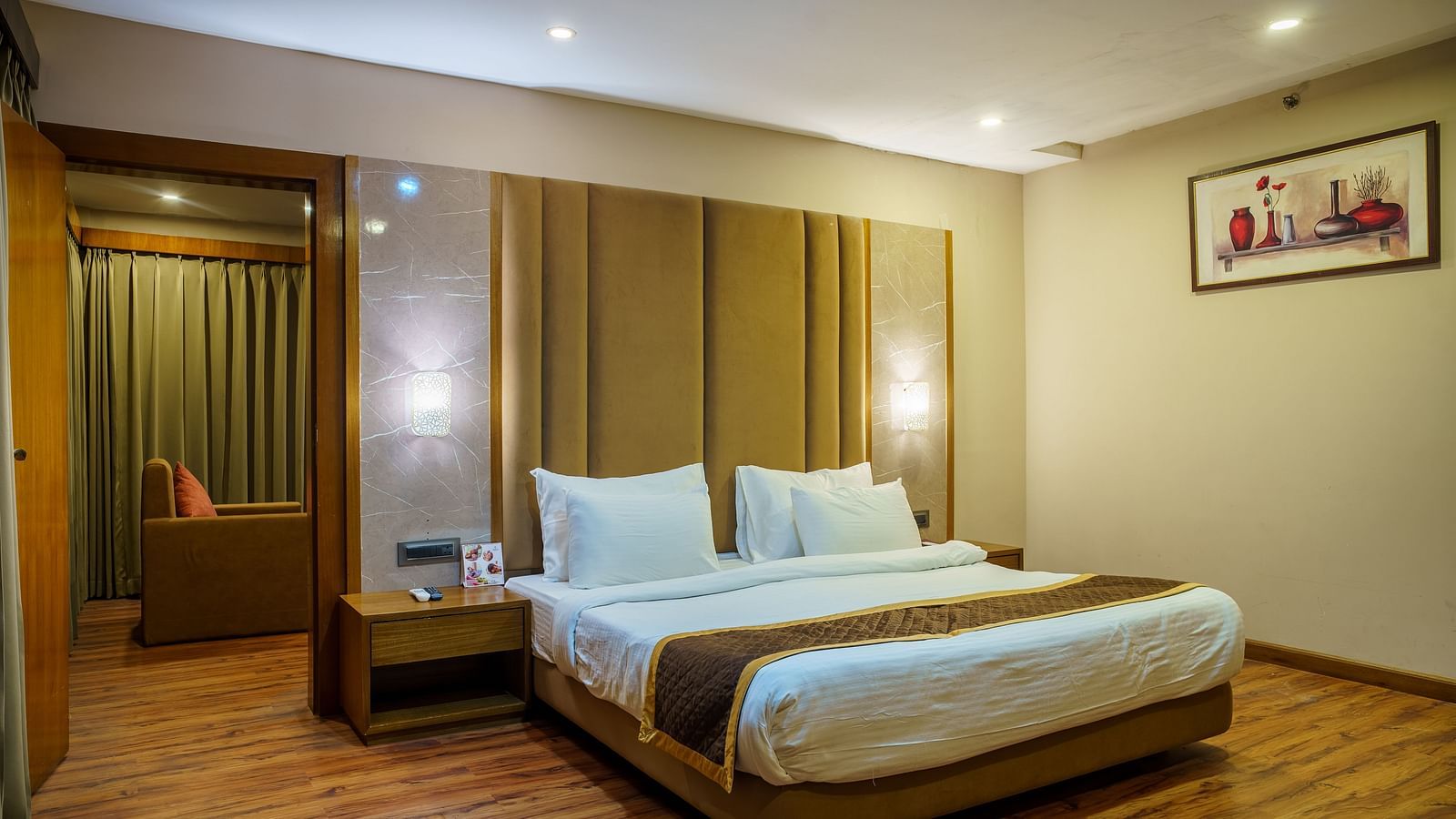 A room at Orsino Spa Resort with a bed featuring a light-coloured headboard, a bedside table, and wooden accents.