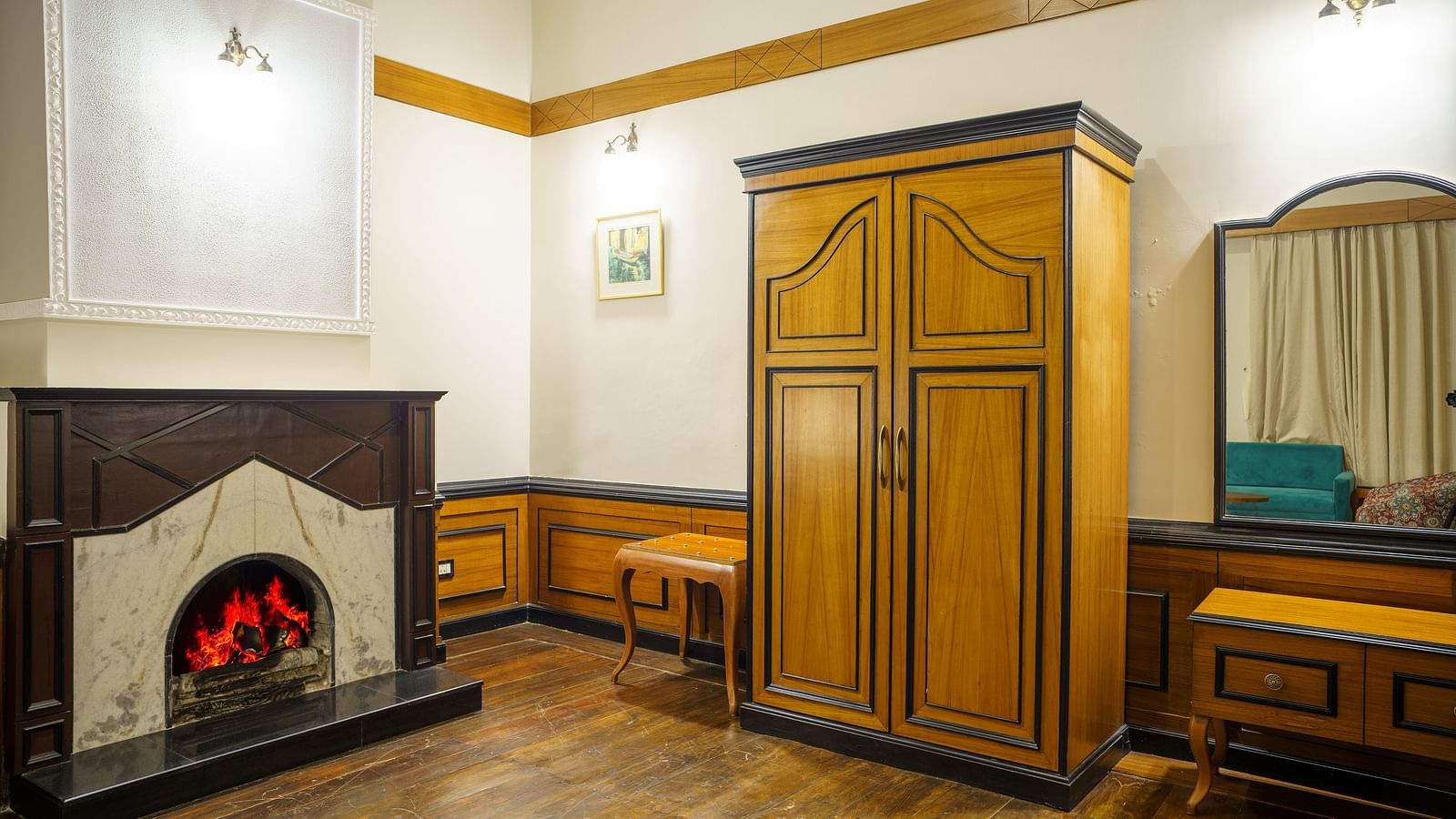 A room at Orsino Spa Resort featuring a large wooden wardrobe, a dressing table with a mirror, and a decorative fireplace with a dark surround.