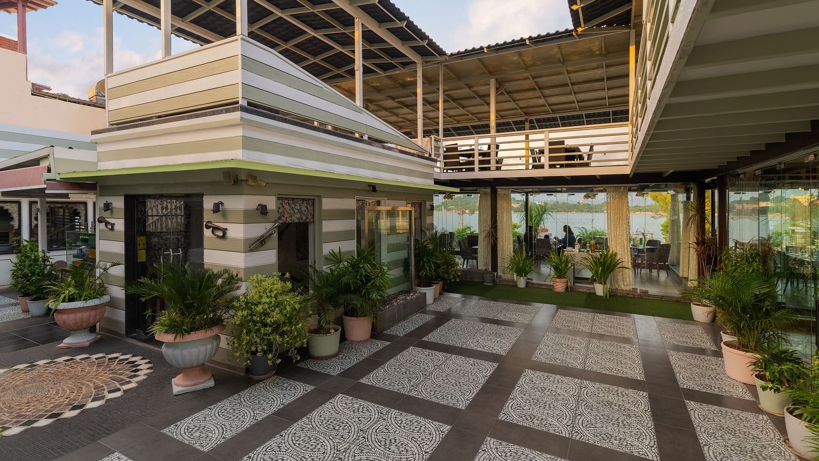 Rooftop restaurant entrance of Panna Vilas Palce features potted plants for decoration, with glass panels separating the dining area.