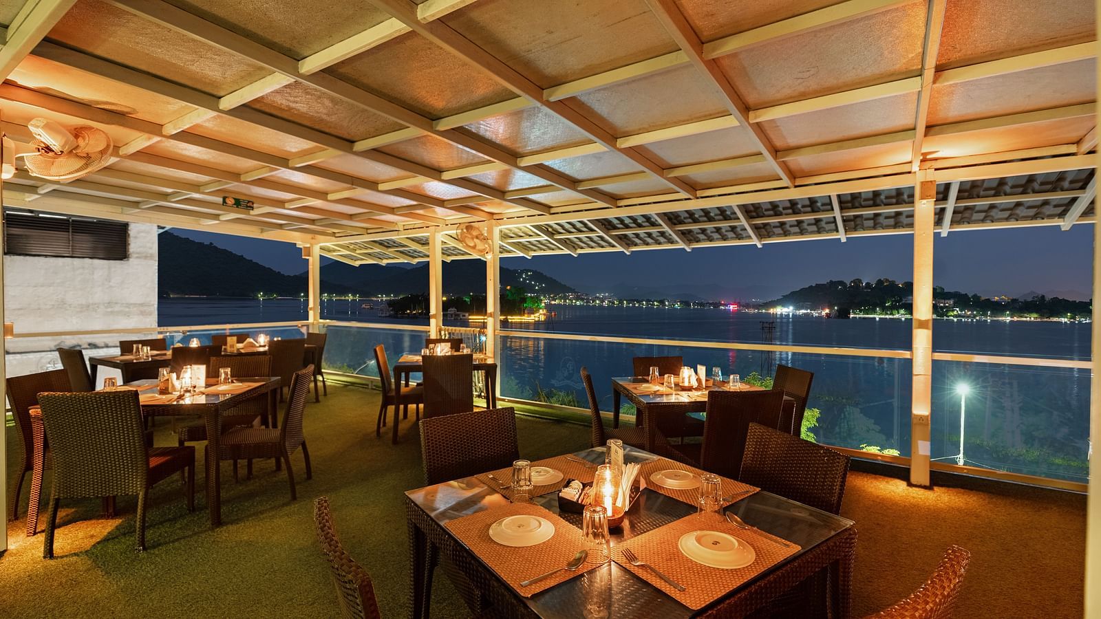 Restaurant area at Panna Vilas Palace features a four-seater table surrounded by wooden chairs, beautifully illuminated by warm lighting, creating an inviting night view - Panna Vilas Palace, Udaipur