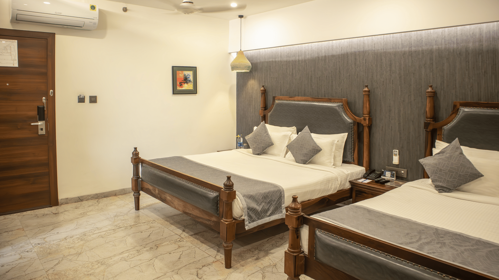 Wide view of a Bedroom at showcasing modern interior with twin beds and a door opening to another room |at Papaya Tree Hotels.