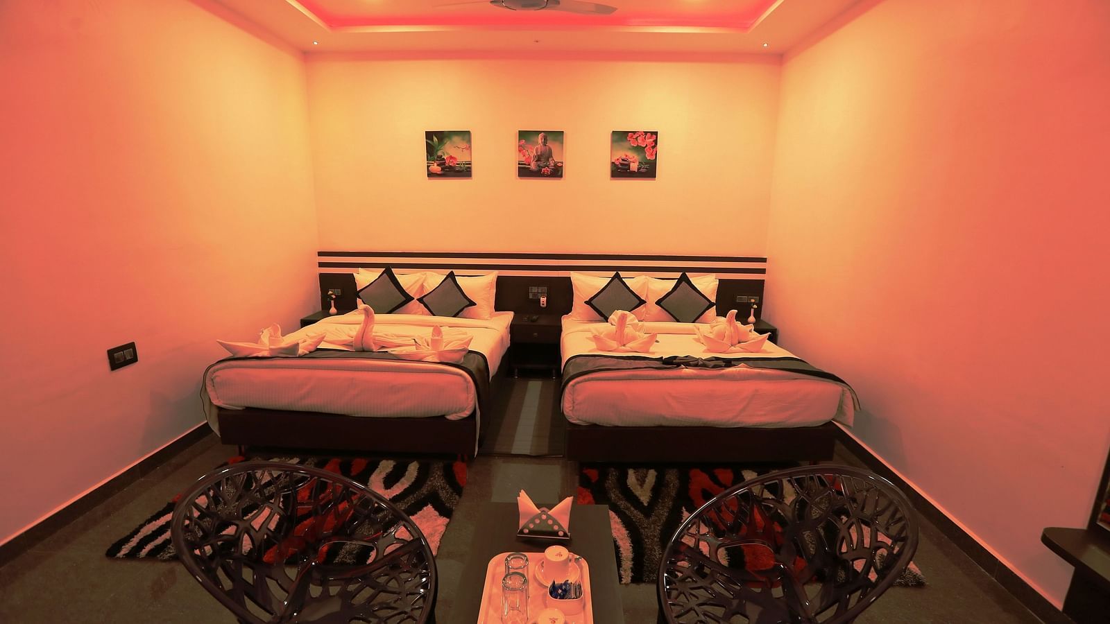 Image of a dimly lit room with two beds and a seating area at Parampara Residency, Kushalnagar.