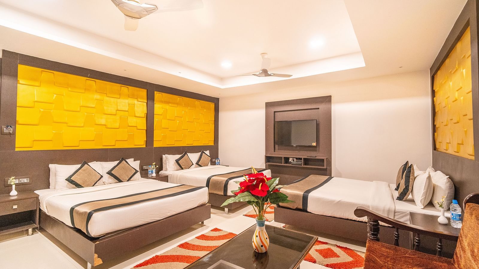 Image of a room with three beds and a sitting area at the side at Parampara Residency, Kushalnagar. 