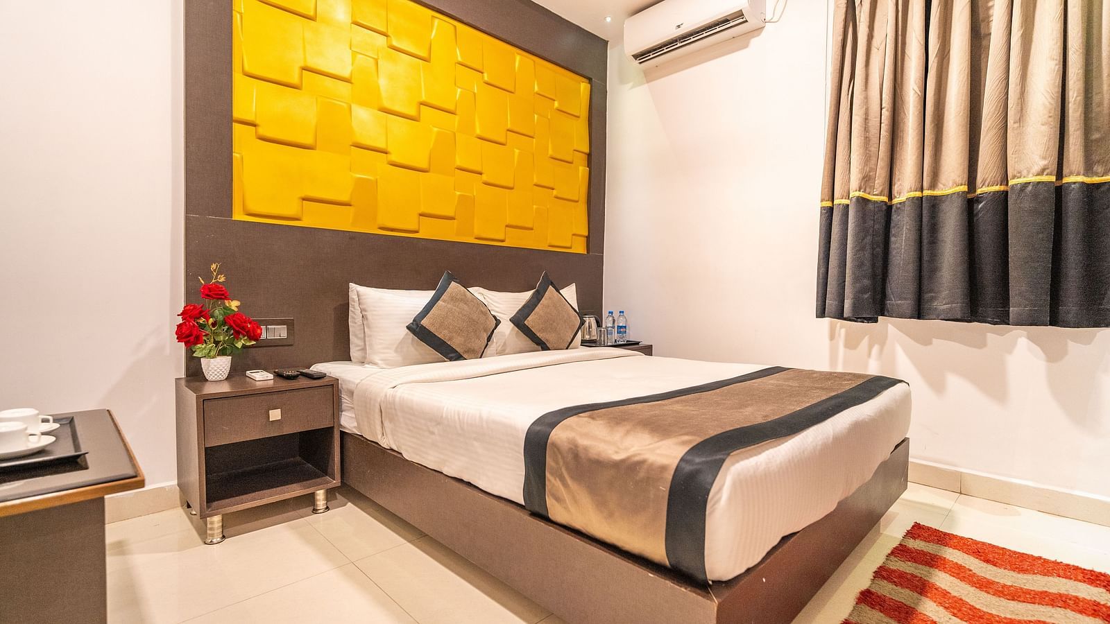 Image of a room with a bed and a side table with flowers on it at Parampara Residency, Kushalnagar.