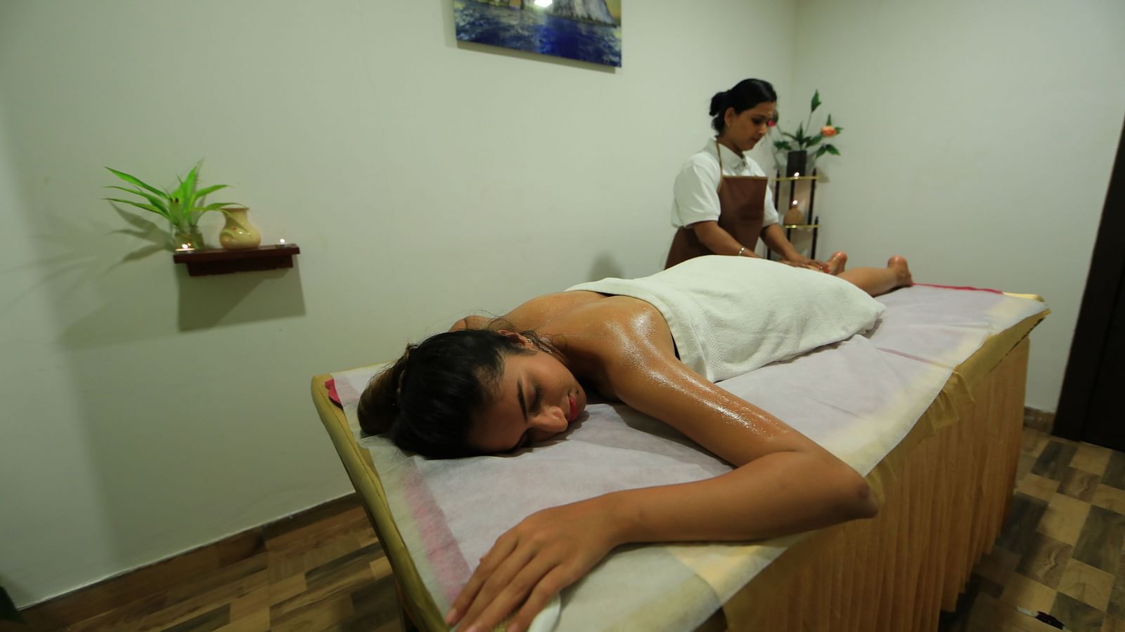 Image of a woman lying on a spa bed with a woman standing beside the bed at Parampara Resort & Spa, Kushalnagar.