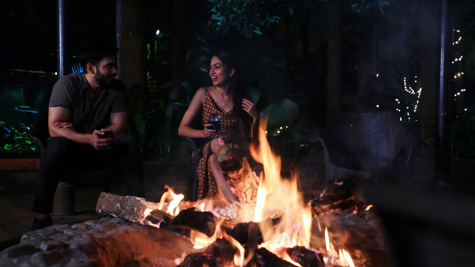 Image of two people sitting beside a bonfire at Parampara Resort & Spa, Kushalnagar.