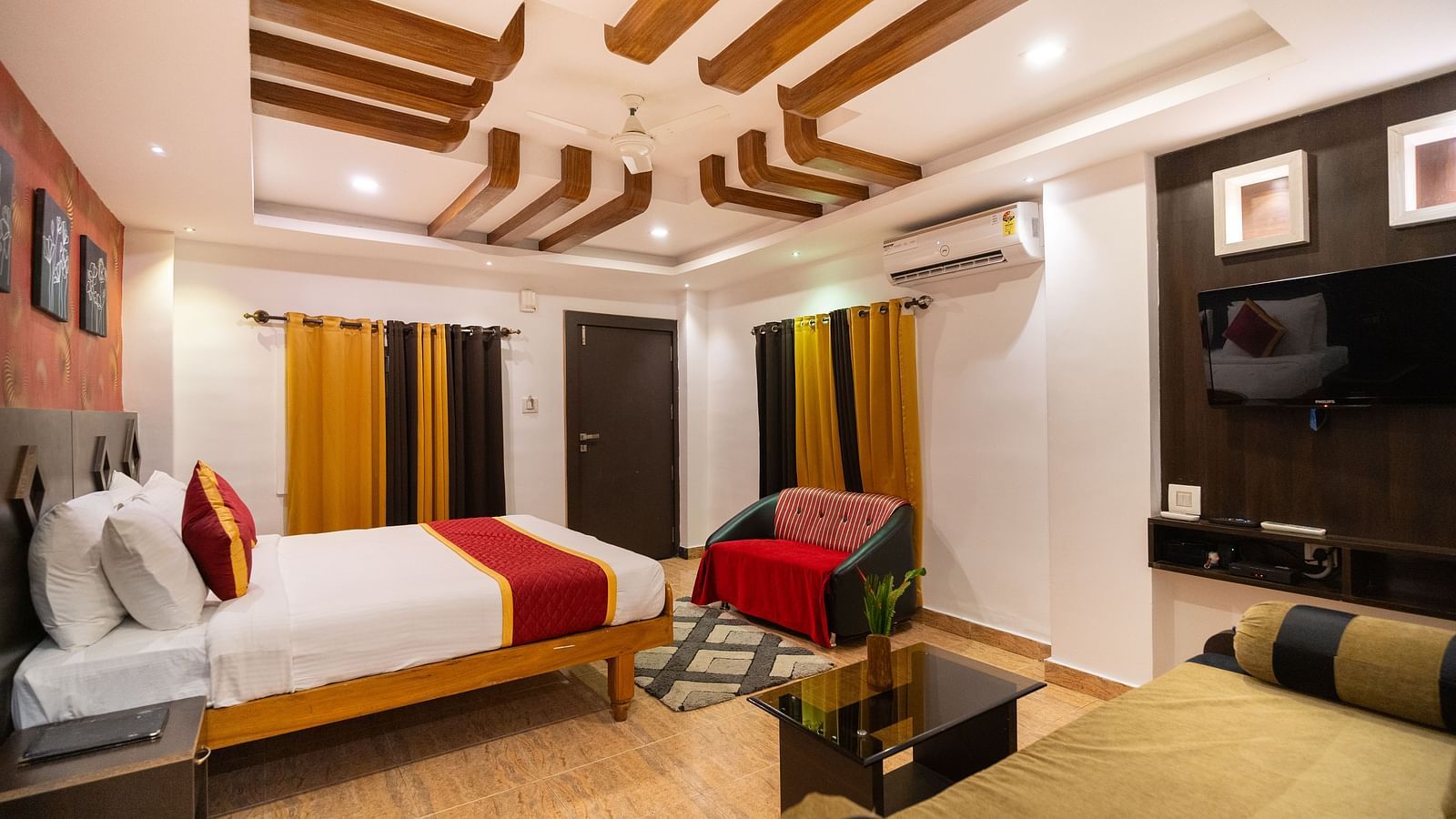 Side view of a room with a bed and a sofa in front of the bed at Parampara Resort & Spa, Kushalnagar.