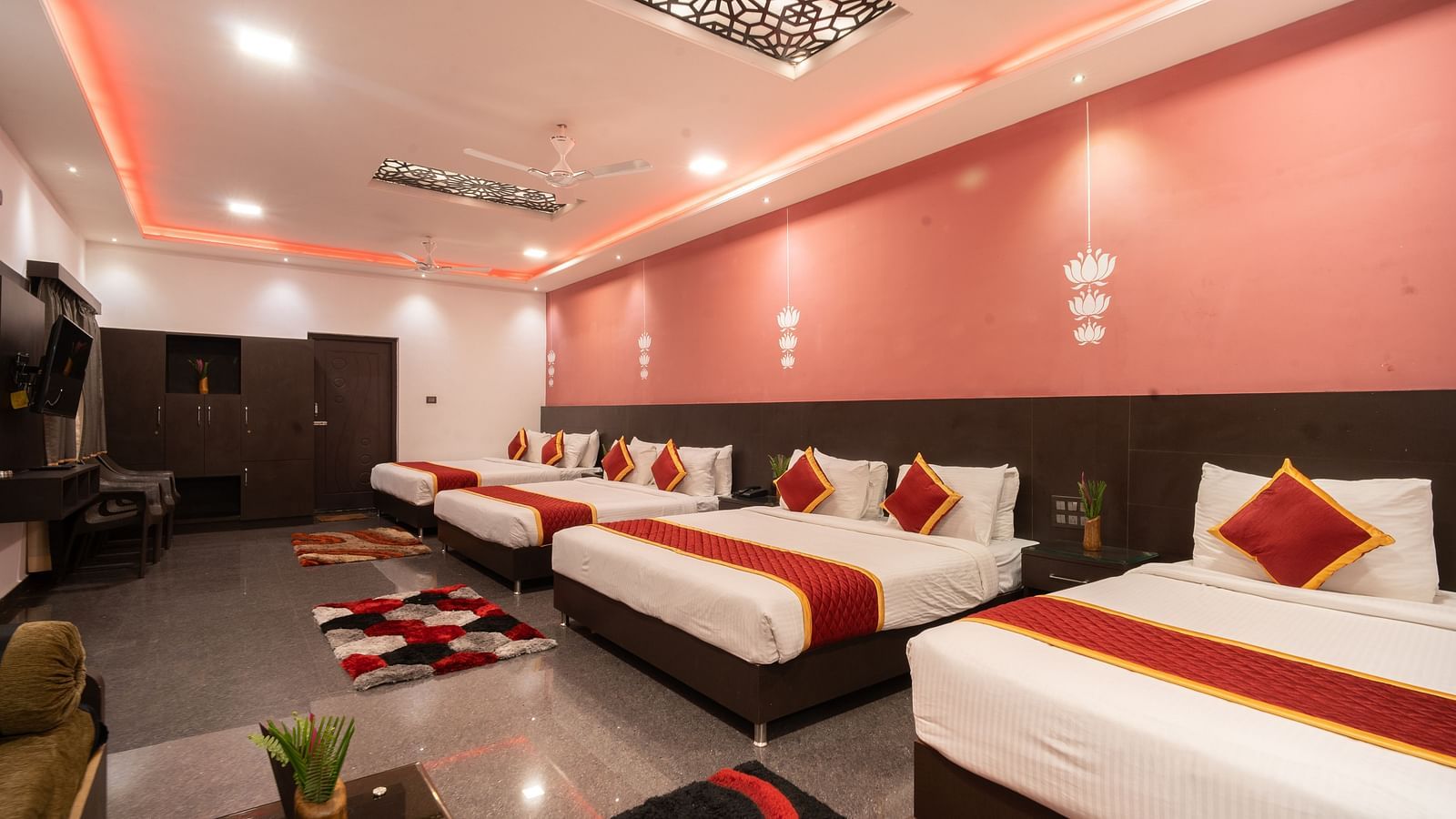 Image of a room with four beds with rugs placed in front of each bed at Parampara Resort & Spa, Kushalnagar.