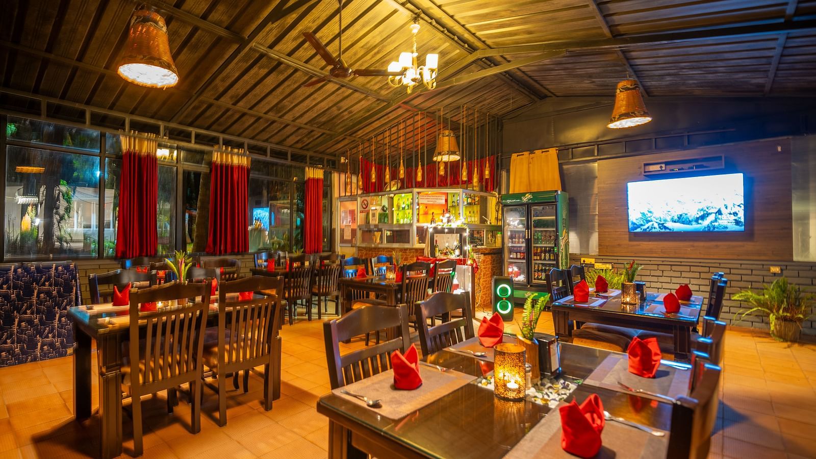 Image of a dining section with wooden tables and chairs at Parampara Resort & Spa, Kushalnagar.