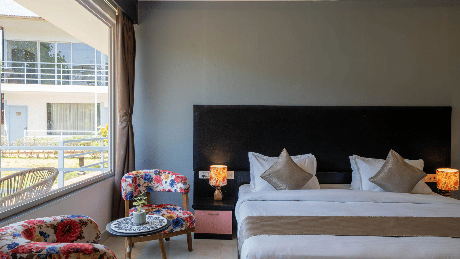 Close-up of a king size bed, a cosy seating area with a coffee table and chairs, and a sun-lit window in our room - Perfectstayz Koko Maya