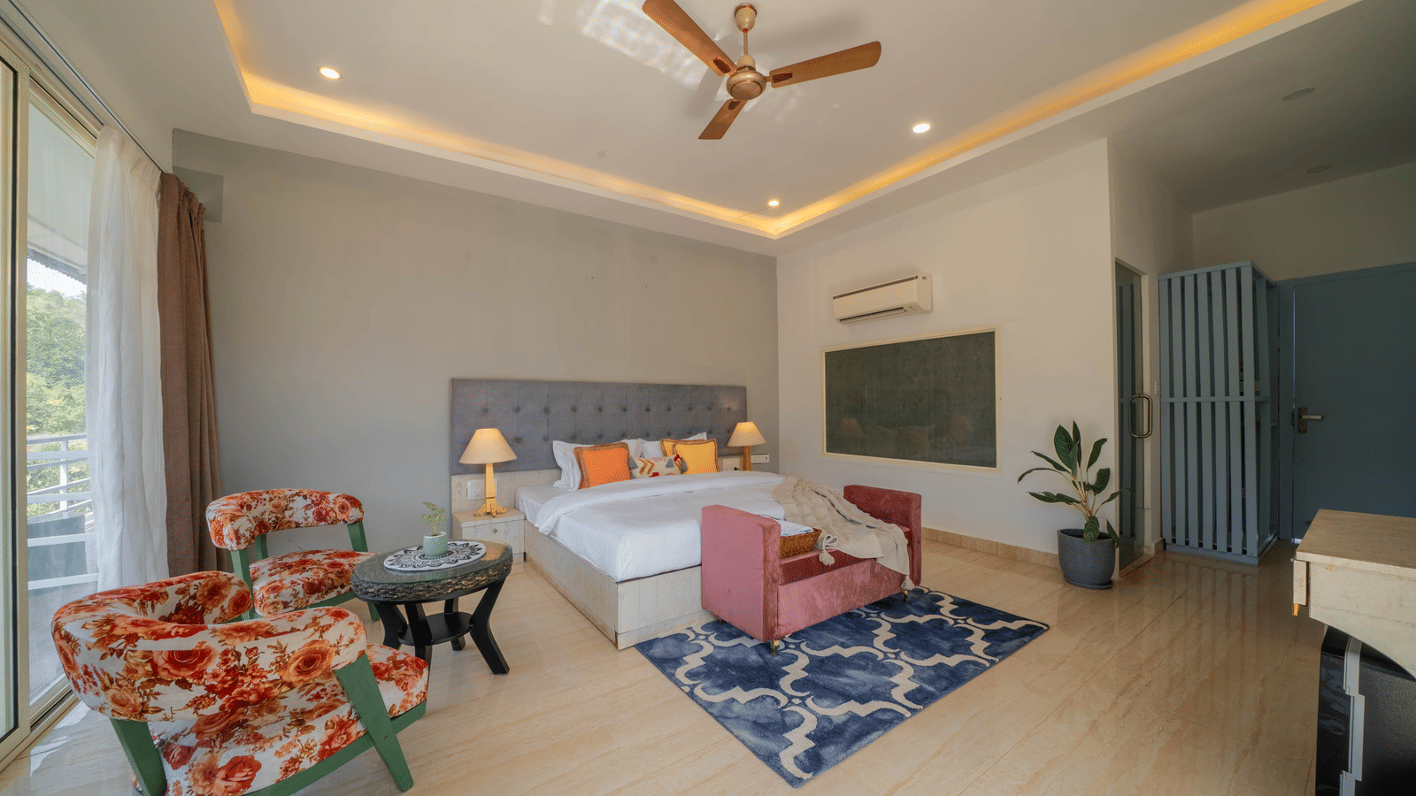 A room featuring a king size bed, a bed bench, a seating area, and warm ambient lighting - Perfectstayz Koko Maya