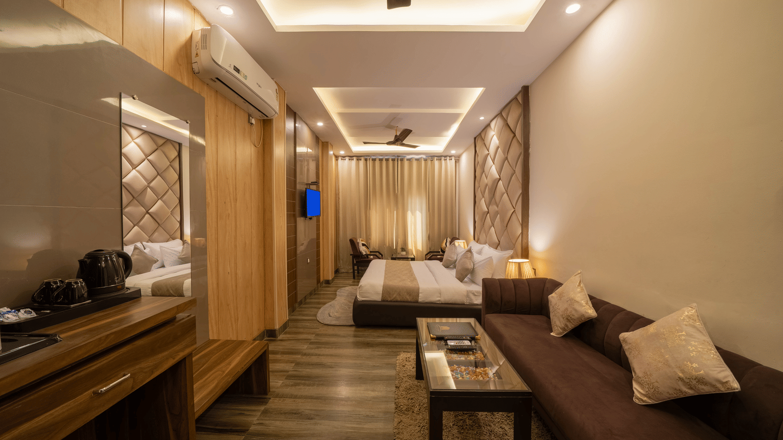 Long, spacious hotel room with a bed and a separate lounge area featuring a sofa and coffee table - Perfectstayz Premium at Har Ki Pauri Road (Ganga Heights)